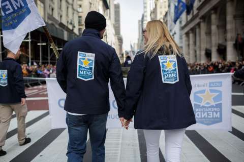 Two people wear Operation Mend jackets during a parade