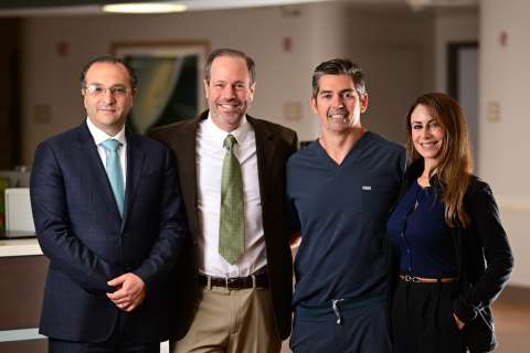 Four colleagues standing together in a modern office hallway