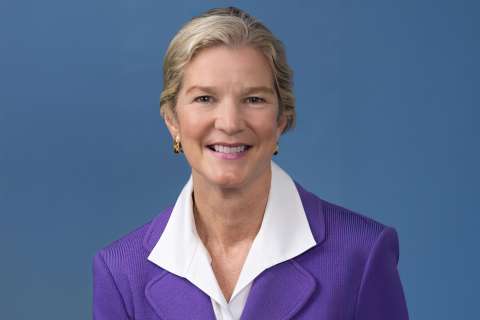 Dr. Elmore in purple blazer and white collared shirt on blue background