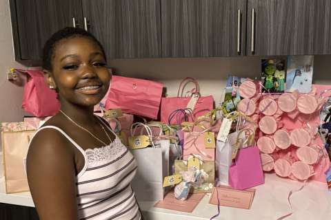 Smiling girl beside table of pink gift bags and wrapped presents