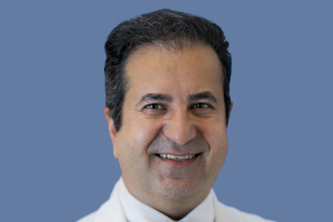 Portrait photo of Bijan Najafi wearing a white lab coat in front of a light blue background.