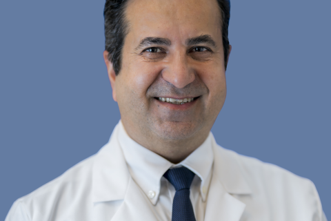 Portrait photo of Bijan Najafi wearing a white lab coat in front of a light blue background.