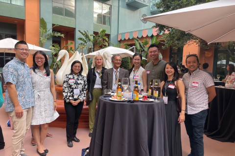  A group of physicians, pharmacists, and nurses stand around a table with drinks at the AGS Annual Scientific Meeting.