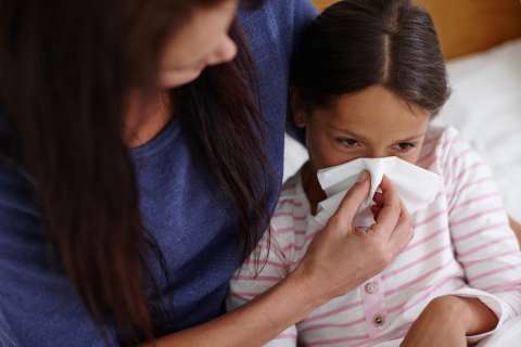 Mom blows her daughter's stuffy nose.