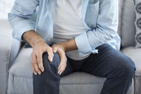 A seated man puts his hands on his right knee.