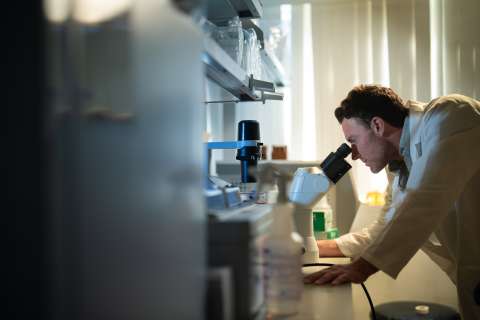 David Nathanson, PhD, looking in a microscope. 