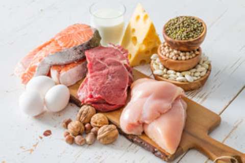 A wooden board with various meats, eggs, cheese, and nuts displayed.