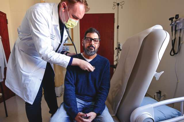 Doctor checking man's heart with stethoscope