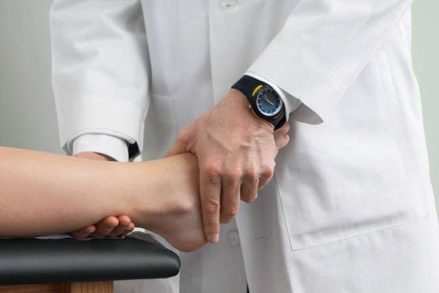 Clinician in white coat holding patient's ankle