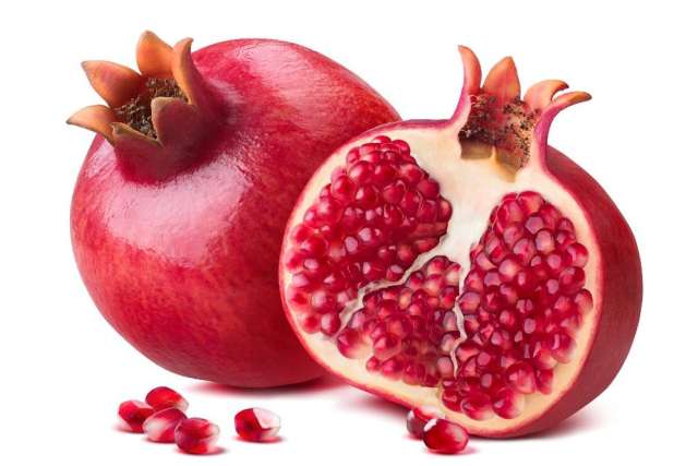 Fresh pomegranates, one whole and one halved, revealing juicy seeds.