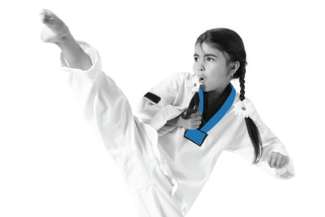 Girl in a martial arts uniform with a blue collar performs a high kick, wearing a determined expression.