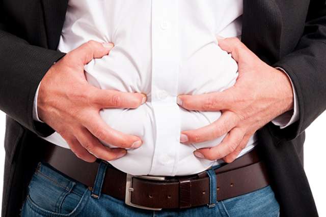 bloating: person clutching abdomen over white shirt