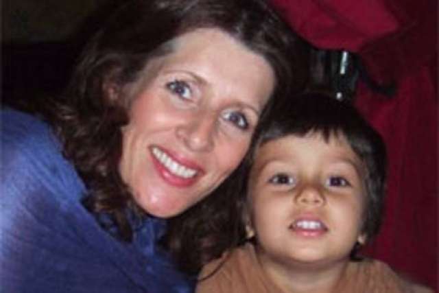 A woman and a child pose together with red fabric in the background.