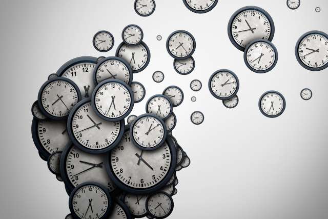 Silhouette of a human head made of many analog clocks with clocks drifting away.
