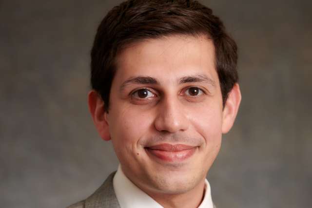 Headshot of person in gray suit and blue tie