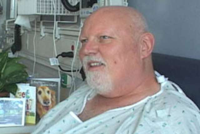 Kidney Transplant Patient seated in hospital bed wearing a gown