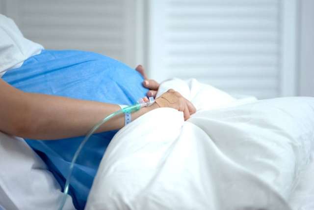 Pregnant woman in hospital bed with hand on belly