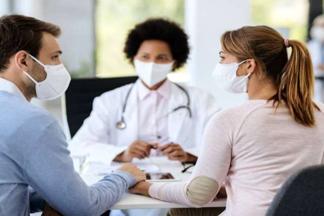 Couple in masks consulting doctor about fertility