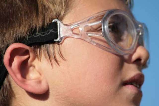 Close-up of an ear with short brown hair and a black headband, shown against a blue background.