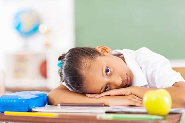 Young girl in school with head on desk