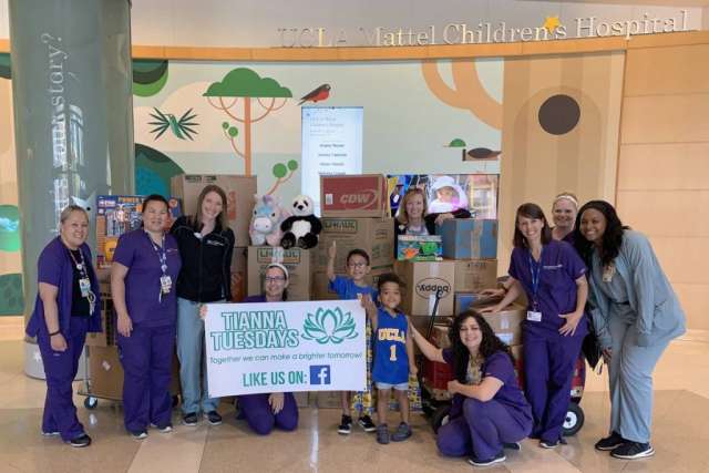 Hospital staff and children pose with donated toys and a "Tianna Tuesdays" banner at UCLA Mattel Children’s Hospital.