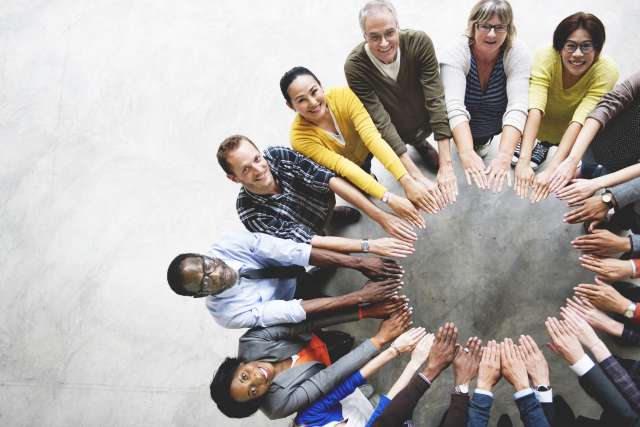 Group of people in a circle extending their arms into the center