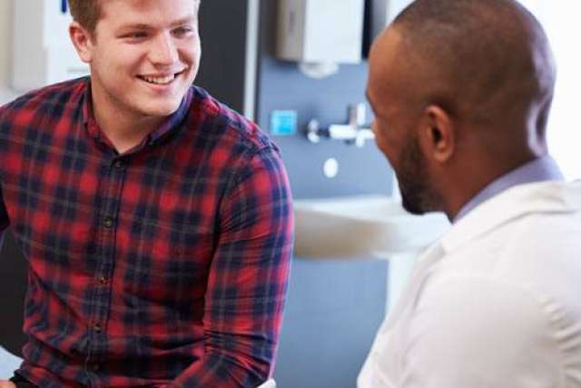 Two men sitting across from each other. The man on the left is holding a pen and paper