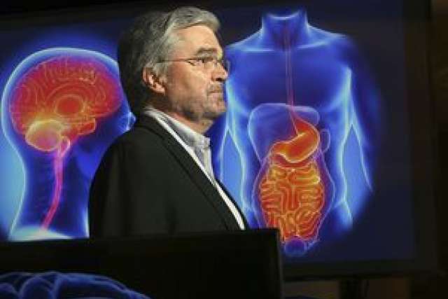 Dr. Mayer stands beside a projected image of human anatomy.