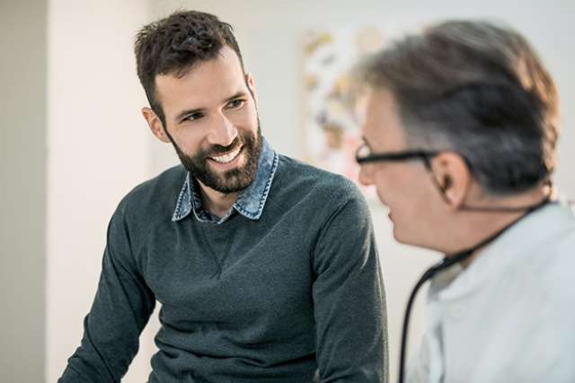 Healthcare professional speaking with a person during a consultation in a clinical setting.