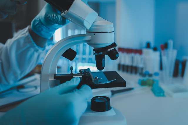 Researcher working at a microscope in a cancer lab