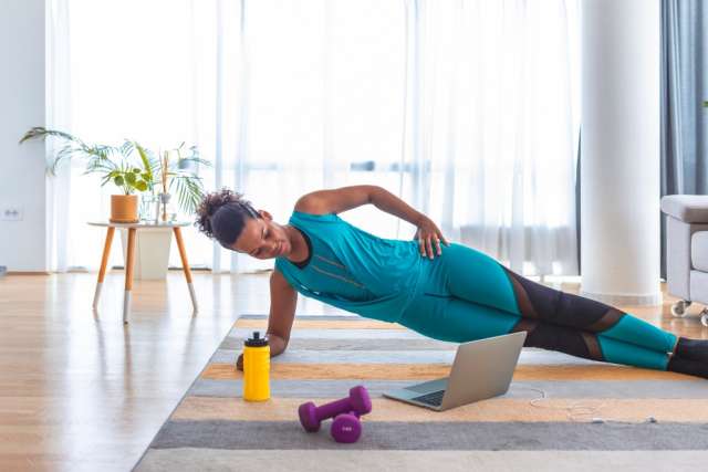 Woman doing side plank with dumbbell