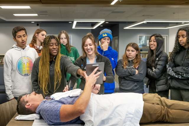 Dr. Maryte Gylys speaks to students at El Segundo High School as Dr. Dane Saksa plays the role of the patient. Drs. Gylys and Saksa, along with fellow members of the UCLA Health Department of Anesthesiology and Perioperative Medicine, were at the school as part of Project Lead the Way, a biomedical science curriculum aimed at inspiring high school students to pursue medical careers. (Photo by Joshua Sudock/UCLA Health)
