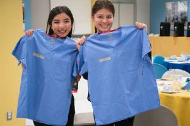 Two individuals holding up blue shirts with the word "Turner" visible.