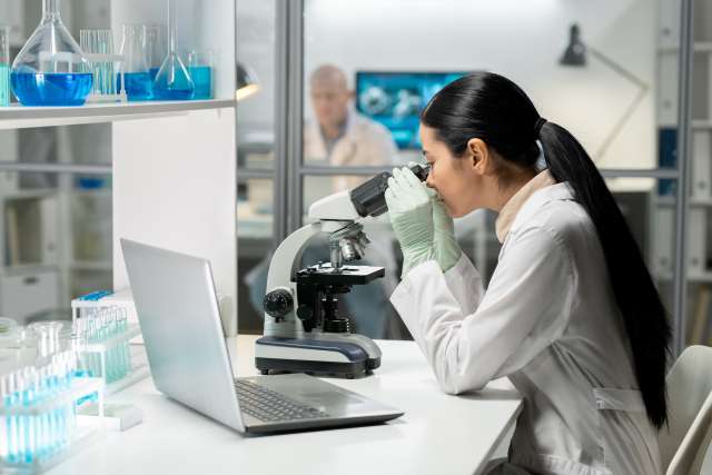 Female research looking into a microscope
