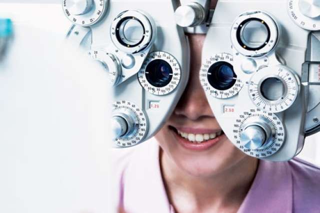 Close-up of an eye examination device with multiple dials and lenses used for vision testing in an optometry setting.