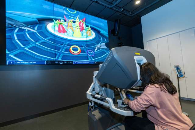 A photo of third-year medical student Amulya Vadlakonda using a robotic surgery simulator at Rosenfeld Hall opening event.