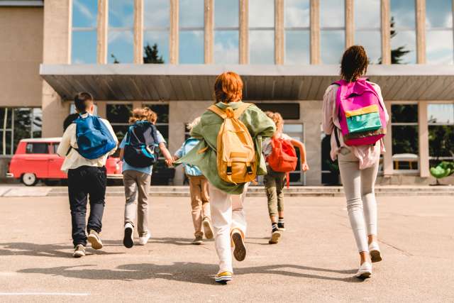Children wearing backpacks running to school 