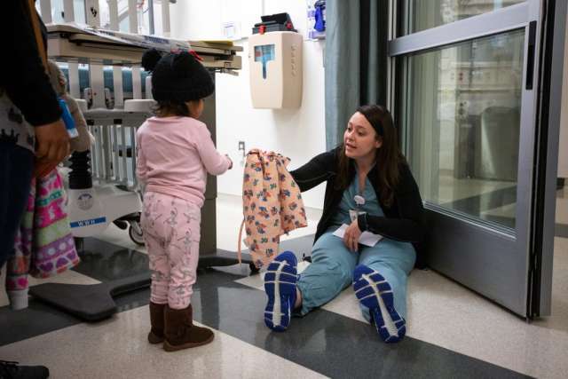 Karleen Wray handing a dress to two year old Genesis