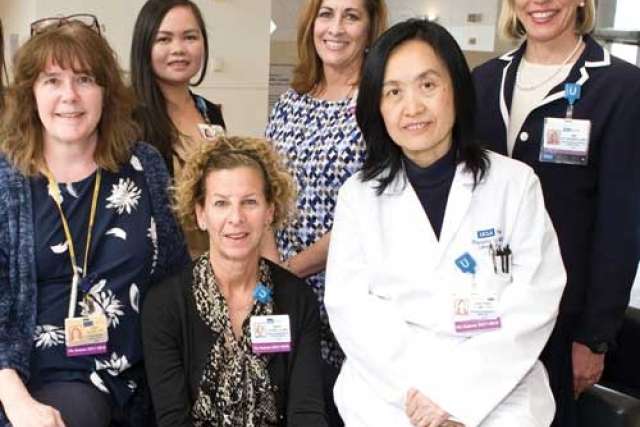 Group of healthcare professionals posing together, some wearing ID badges and one in a white lab coat.