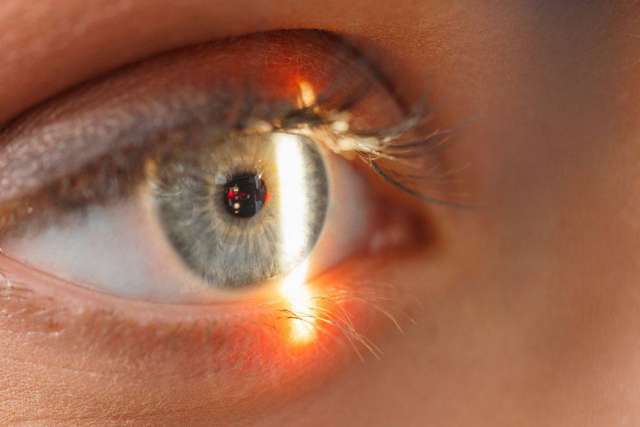 Eye close-up with vertical light reflection and orange flare