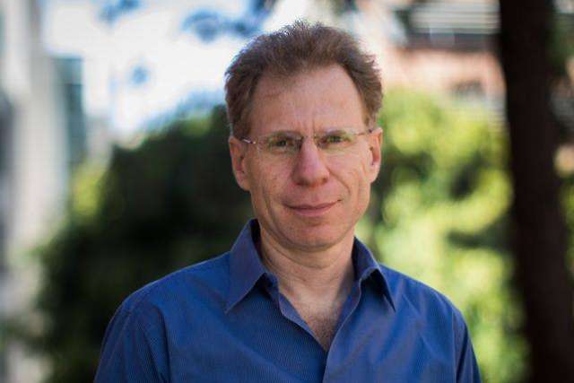 portrait of Leonid Kruglyak in a blue shirt and glasses outdoors