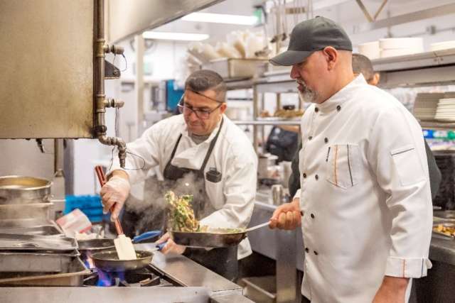 UCLA Health cook Mario Gonzalez prepares eggs while executive chef Gabriel Gomez works on a vegetable medley in the medical center kitchen