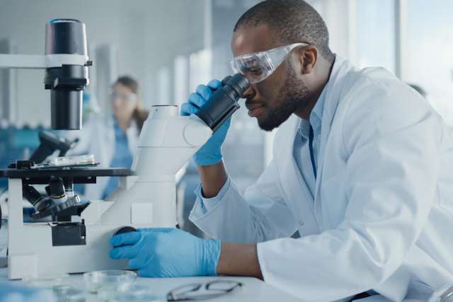 A toxicologist looking through a microscope