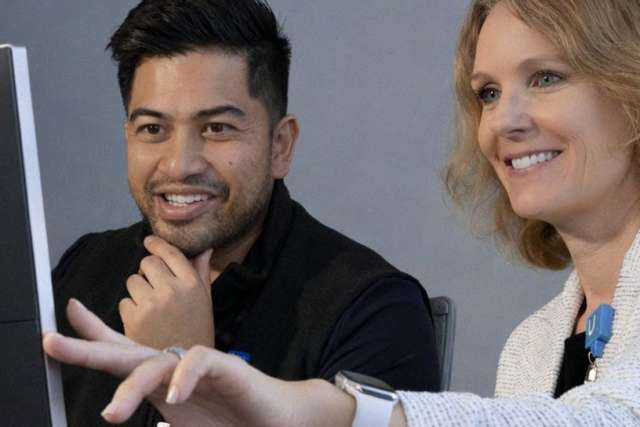 Donna Wellbaum points at a computer screen while a Michael Wellig observes attentively.