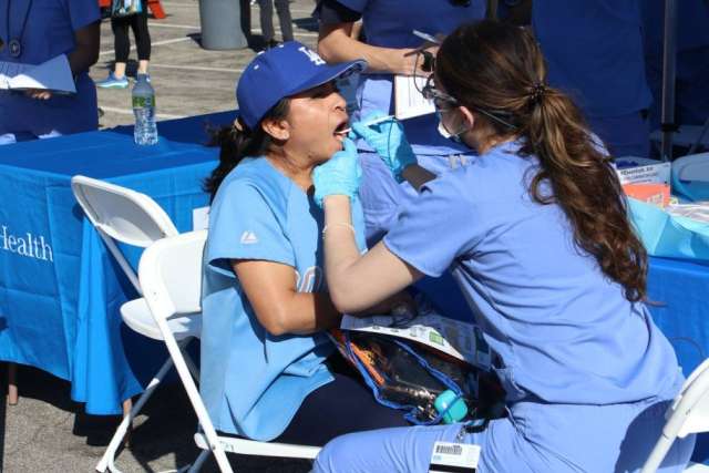 Healthcare worker in blue scrubs attending to seated woman at Fam Care Village