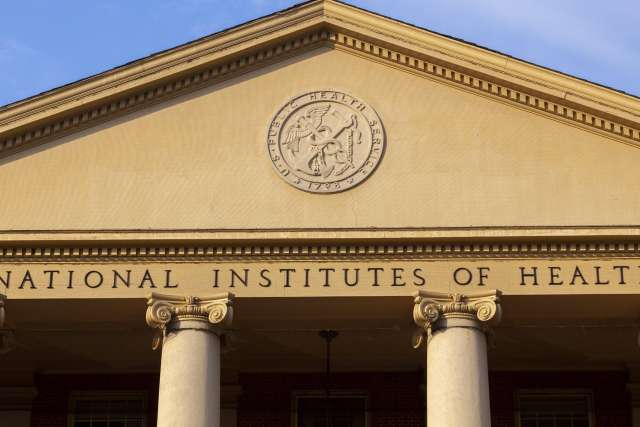  A classical-style building facade with the words "National Institutes of Health" inscribed below a triangular pediment.