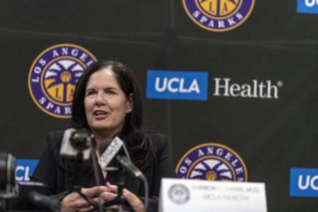 A professional headshot of Dr. Sharon Hame, a woman with dark hair, speaking at a podium with a UCLA Health and LA Sparks banner in the background.