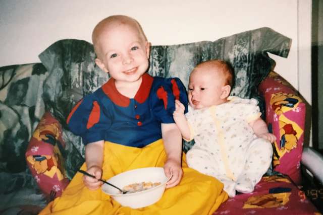 A toddler and baby sitting on a couch