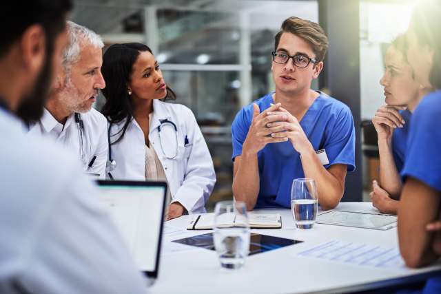 Medical team in scrubs talking around a conference table