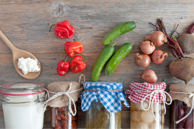 jars of yogurt, peppers, cucumbers, onions, and beets displayed on a table